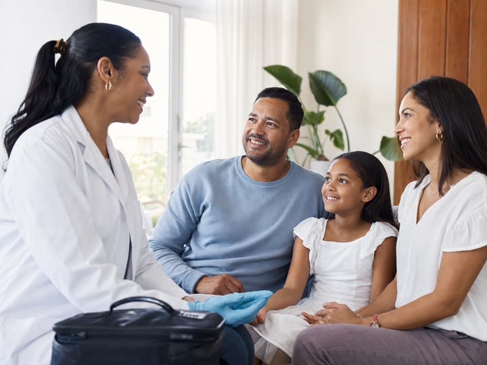 Familia recibiendo con confianza a una profesional de laboratorio en casa